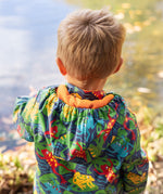 The back of a toddler wearing the Frugi be hoppy puddle buster coat showing the hood detail and orange fleece inside liner. 