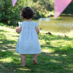 Child wearing the Frugi  Beach Hut Blue Stripe Birdie Body Dress showing the back of the dress