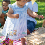 Child wearing the Frugi  Beach Hut Blue Stripe Birdie Body Dress showing the front of the dress