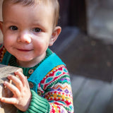 A child wearing the Frugi fowey bear fairisle organic cotton knitted jumper. underneath a blue coloured cord dungarees. 