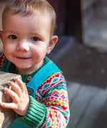 A child wearing the Frugi fowey bear fairisle organic cotton knitted jumper. underneath a blue coloured cord dungarees. 