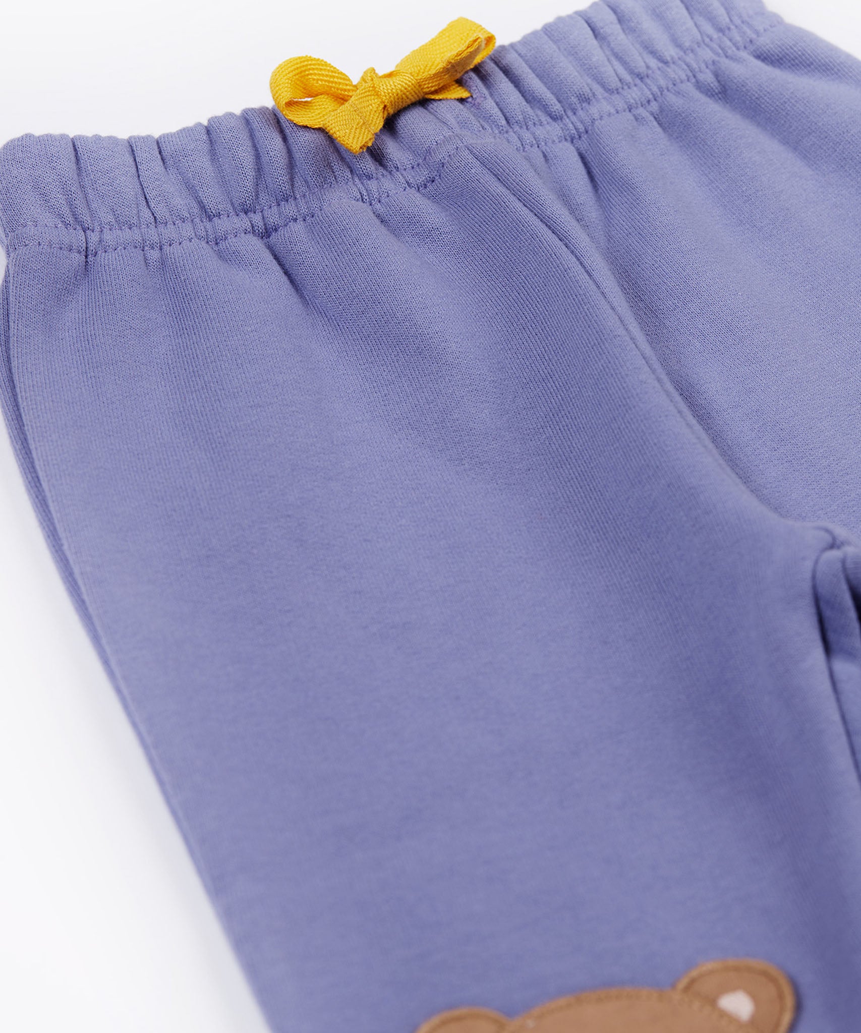A close up of the yellow gold coloured waist tie on the Frugi bear character grape purple coloured children's crawlers.