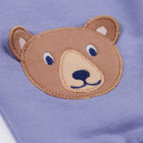 A close up of the brown bear applique on the knees of the Frugi bear character grape purple coloured children's crawlers.