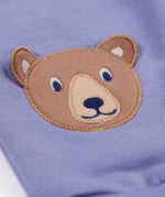 A close up of the brown bear applique on the knees of the Frugi bear character grape purple coloured children's crawlers.