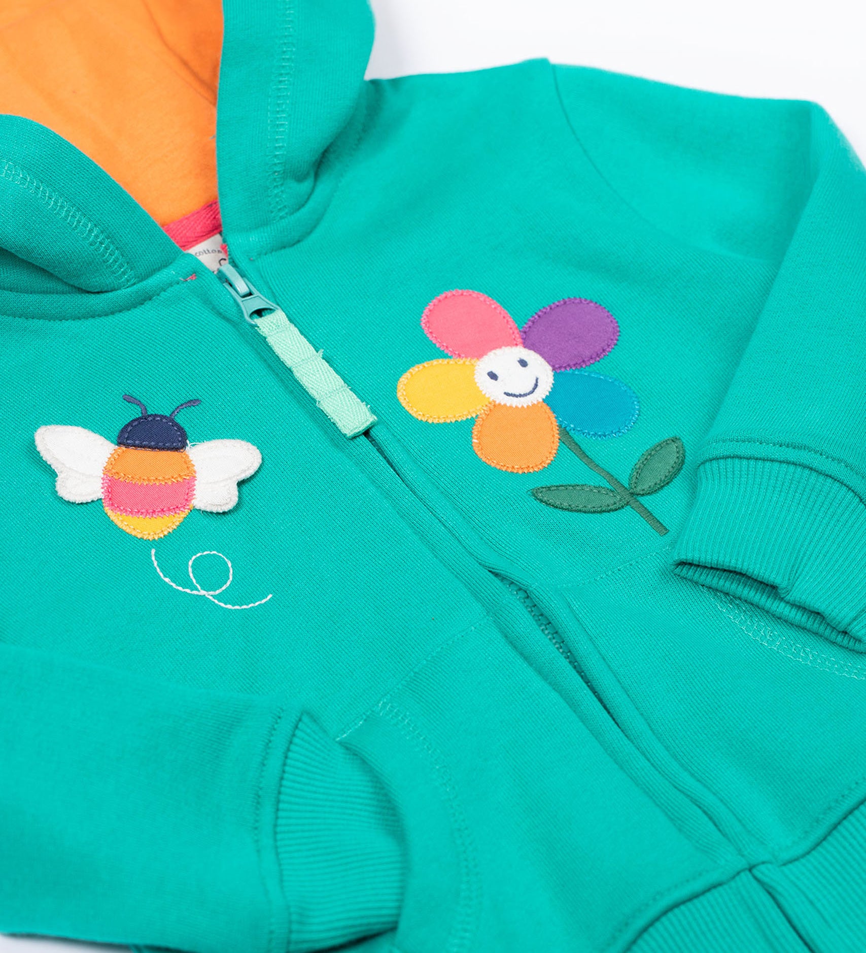 A close up of the Frugi kids carbis hoodie in dragon/bee showing the bee and flower applique detail next to the full length zip