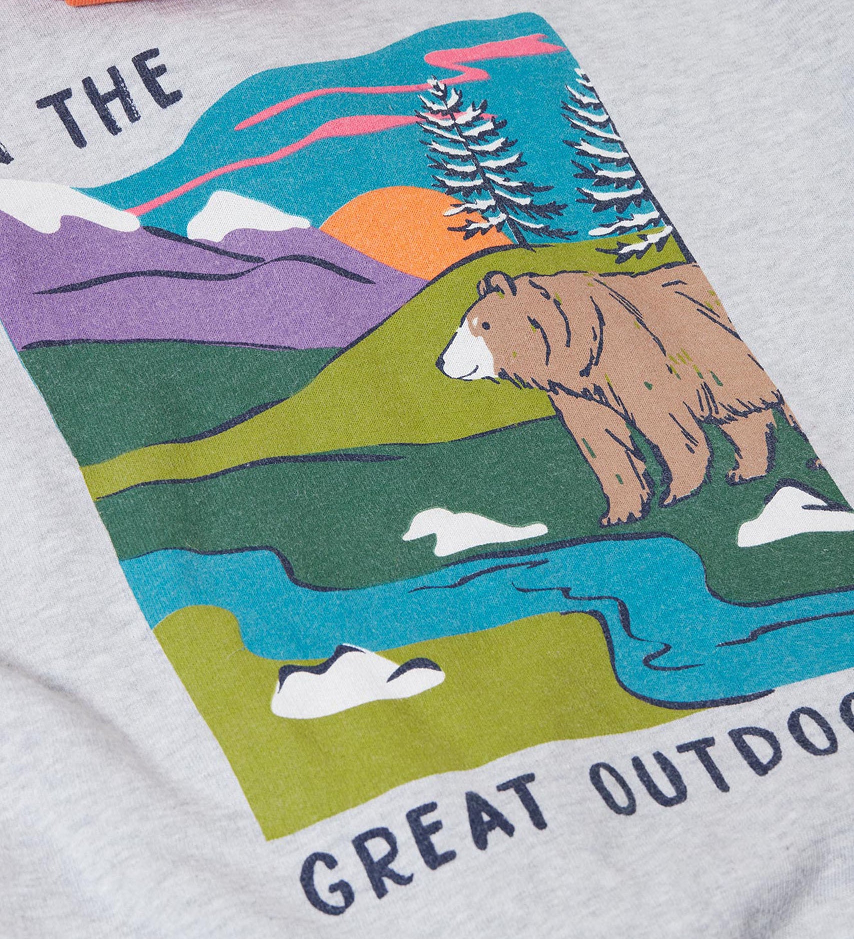 A close up of the Frugi kids ben colour block hopscotch/fun hoodie showing a mountain scene print with a brown bear on the back on organic cotton fabric.