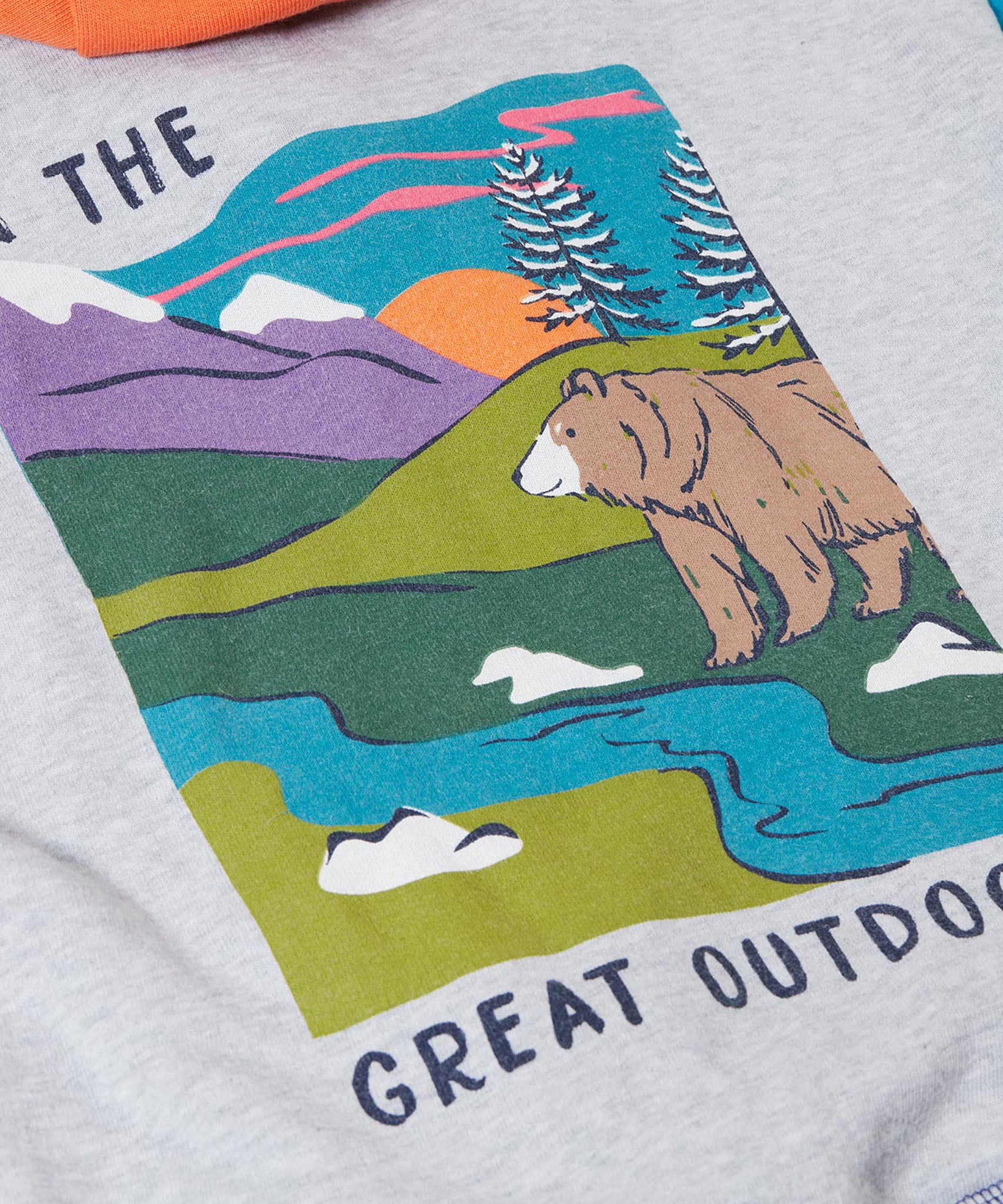 A close up of the Frugi kids ben colour block hopscotch/fun hoodie showing a mountain scene print with a brown bear on the back on organic cotton fabric.