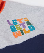 A close up of the Frugi kids ben colour block hopscotch/fun hoodie showing the lets get wild slogan near the shoulder on organic cotton fabric.