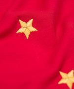 A close up of the gold embroidered star detail on the front of the Frugi Berry Red Reindeer Terrific Circular Organic Cotton long sleeved kids Top. A red coloured children's top with a festive reindeer applique and gold stars on the front. This top is a part of a wide range of organic cotton clothing for children available here at Babipur. 