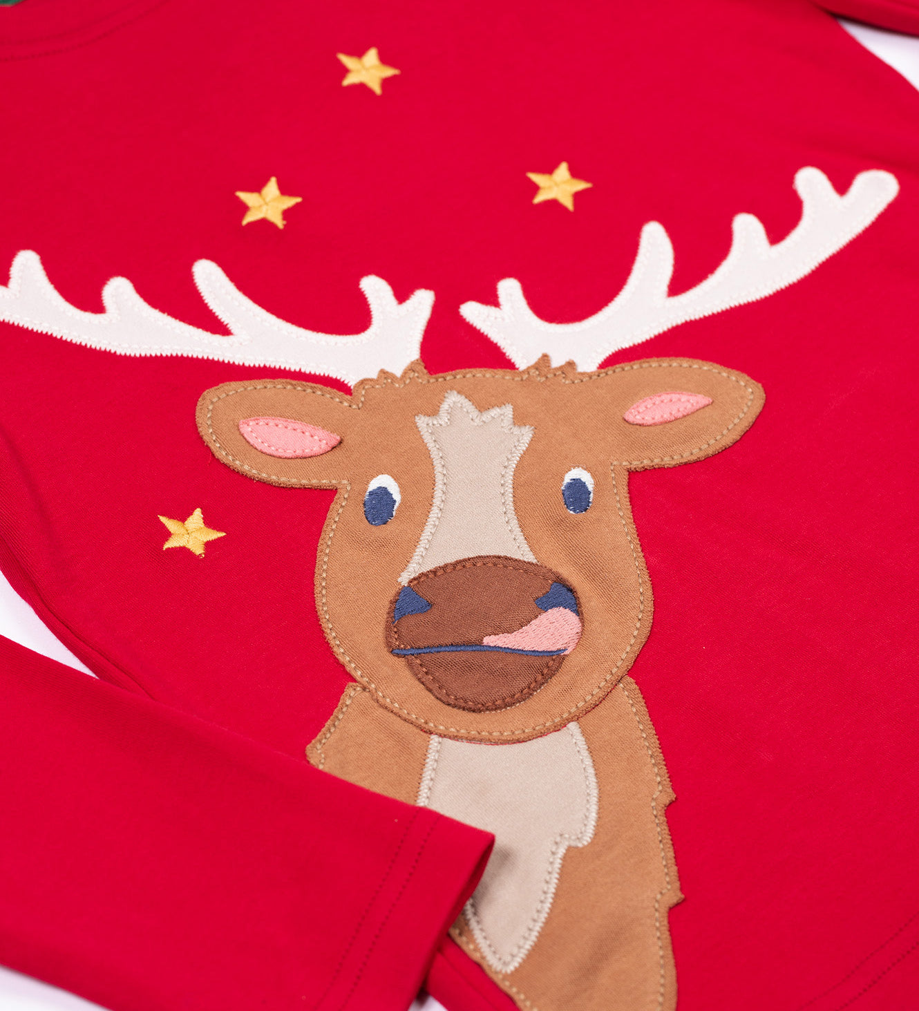 A close up of the reindeer applique on the front of the Frugi Berry Red Reindeer Terrific Circular Organic Cotton long sleeved kids Top. A red coloured children's top with a festive reindeer applique and gold stars on the front. This top is a part of a wide range of organic cotton clothing for children available here at Babipur. 
