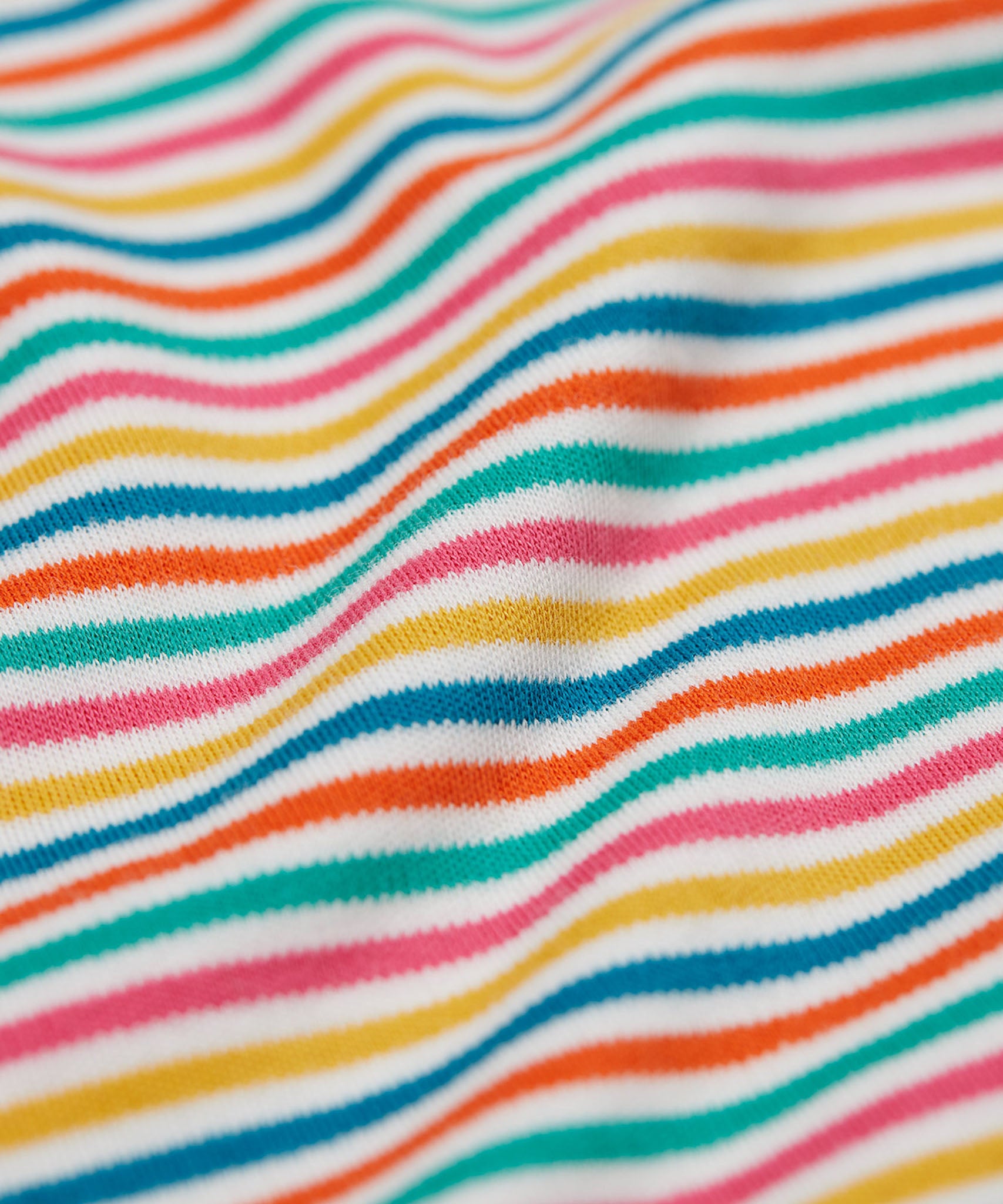 A close up of the Frugi kids multistripe rainbow betty body showing the rainbow stripe detail on the shoulder on organic cotton fabric.