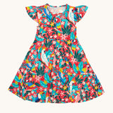 Frugi Morwenna Skater Dress in the Birds Of Paradise print, laid flat. Featuring different exotic birds surrounded by colourful flowers and leaves on a pink background.