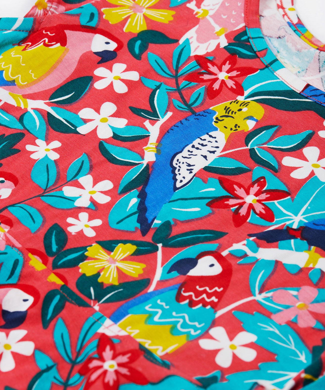 A close up of Frugi Morwenna Skater Dress in the Birds Of Paradise print. Featuring different exotic birds surrounded by colourful flowers and leaves.