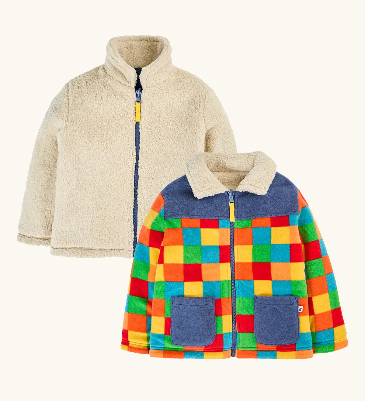 both sides of the frugi fleece jacket, one side in solid cream and one in a bright multicolor patchwork pattern with blue panels and pockets.