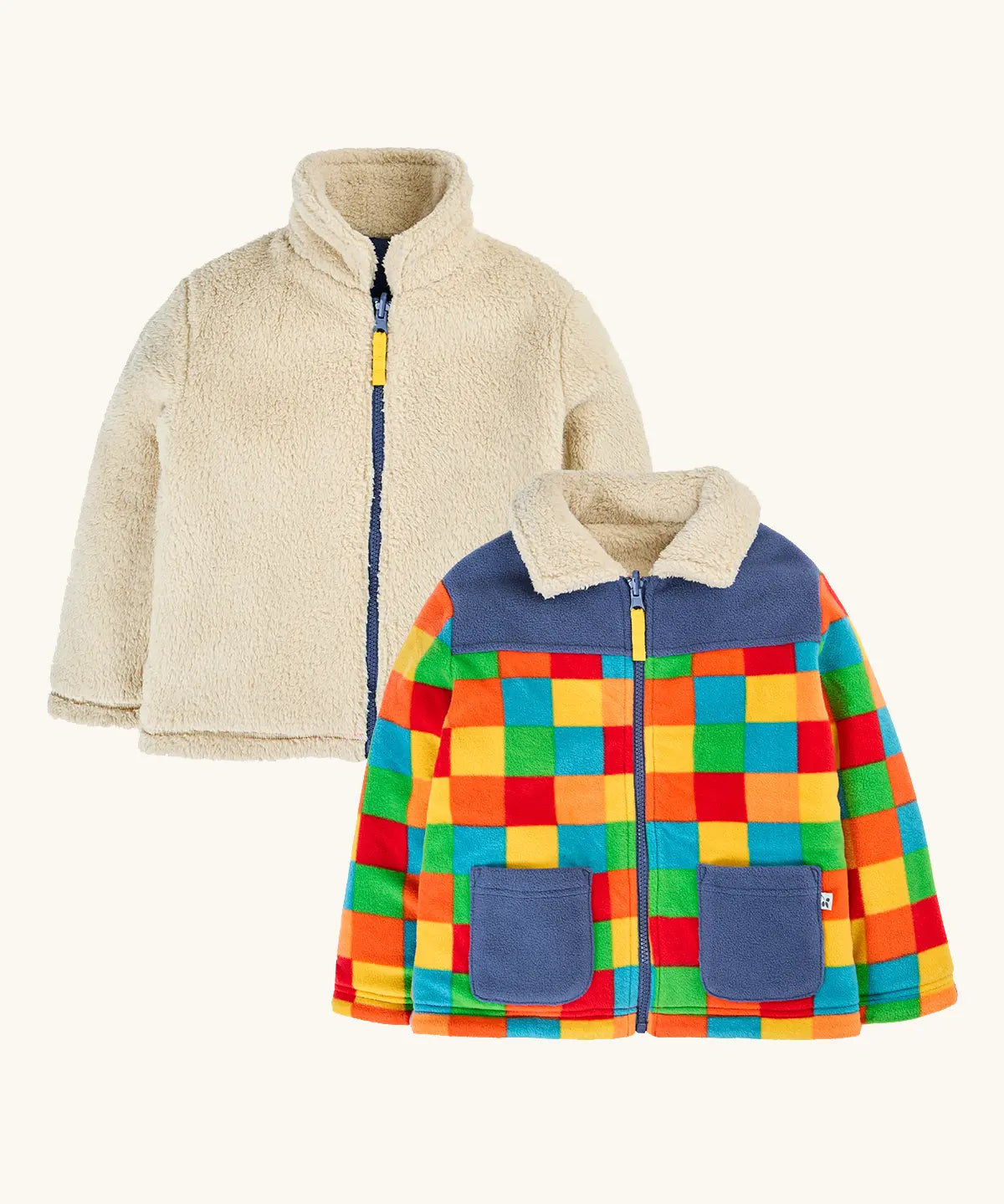 both sides of the frugi fleece jacket, one side in solid cream and one in a bright multicolor patchwork pattern with blue panels and pockets.