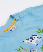 A close up of the Frugi kids bluebird farm life t-shirt  showing the shoulder popper fasteners for easy fitting and light blue neck trim with a yellow trim on the inside on light blue organic cotton fabric.