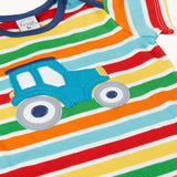Close up of the front of the Frugi blue tractor applique rainbow striped t-shirt. Bands of red, light yellow, green, orange and light blue in-between thinner white stripes.