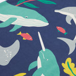 A close up of Frugi Bonnie Dress in Navy Blue, featuring a Sealife print, which includes small fish and larger sea animals, surrounded by colourful seaweed and coral.