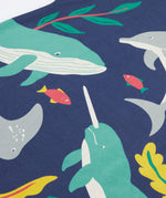 A close up of Frugi Bonnie Dress in Navy Blue, featuring a Sealife print, which includes small fish and larger sea animals, surrounded by colourful seaweed and coral.