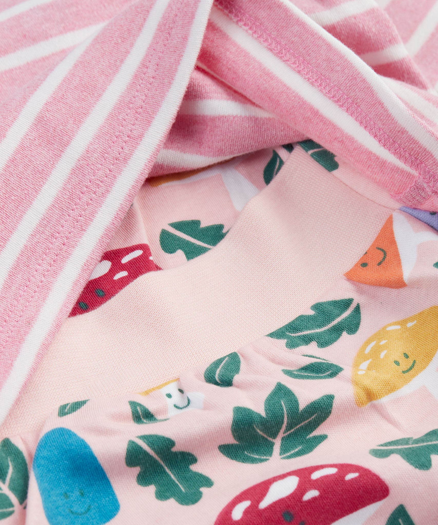 A close up of the top from the frugi kids brooke easy dressing baby grow in fun-guys/pink stripe showing the woodland inspired prints on the bottoms and the soft elasticated waist band detail