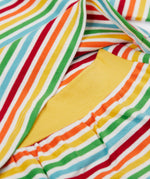A close up of the top from the frugi kids brooke easy dressing baby grow in squirrel/rainbow stripe showing the rainbow inspired striped detail and soft yellow elasticated waist band on organic cotton fabric.