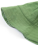 A close up of the Frugi kids green crocodile reversible hat. Showing the other side of the hat which is a plain green organic cotton fabric