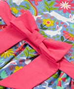 A close up of the Frugi kids bunny bounce skater dress. Showing the pink bow waist band detail pastel purple organic cotton fabric