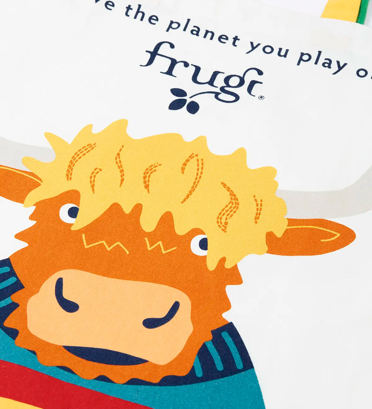 Close up of the Frugi canvas tote bag in soft white with one yellow and one green strap and a highland coo cow design on the front.