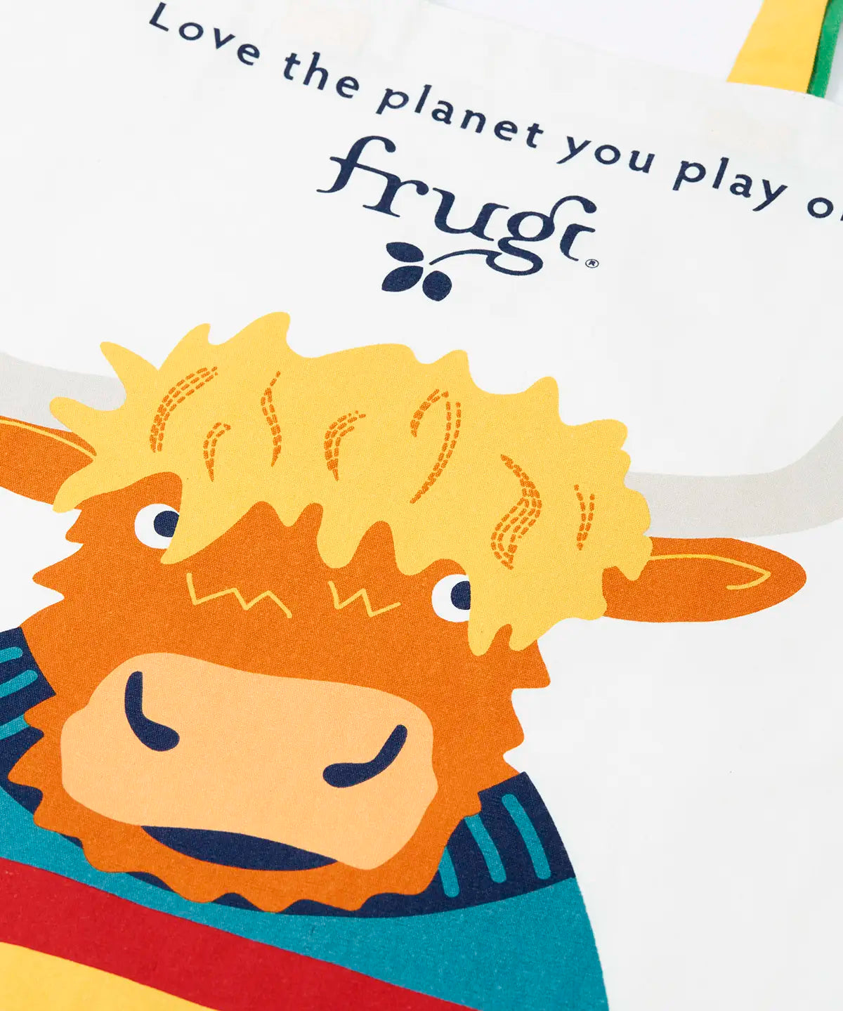 Close up of the Frugi canvas tote bag in soft white with one yellow and one green strap and a highland coo cow design on the front.