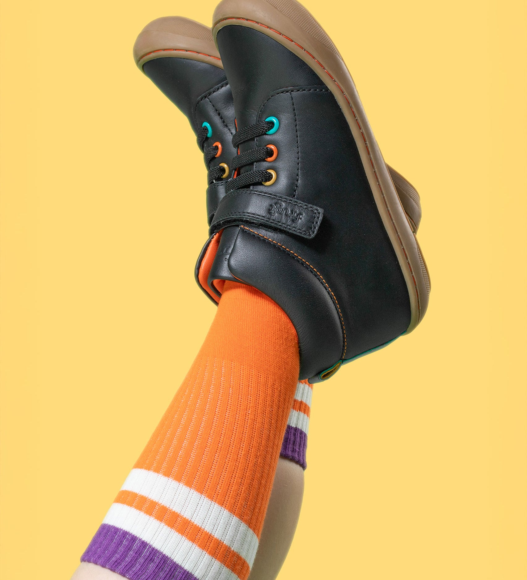 A child wearing the Frugi cape stretch children's lace boot in black leather with salamander orange leather lining. 