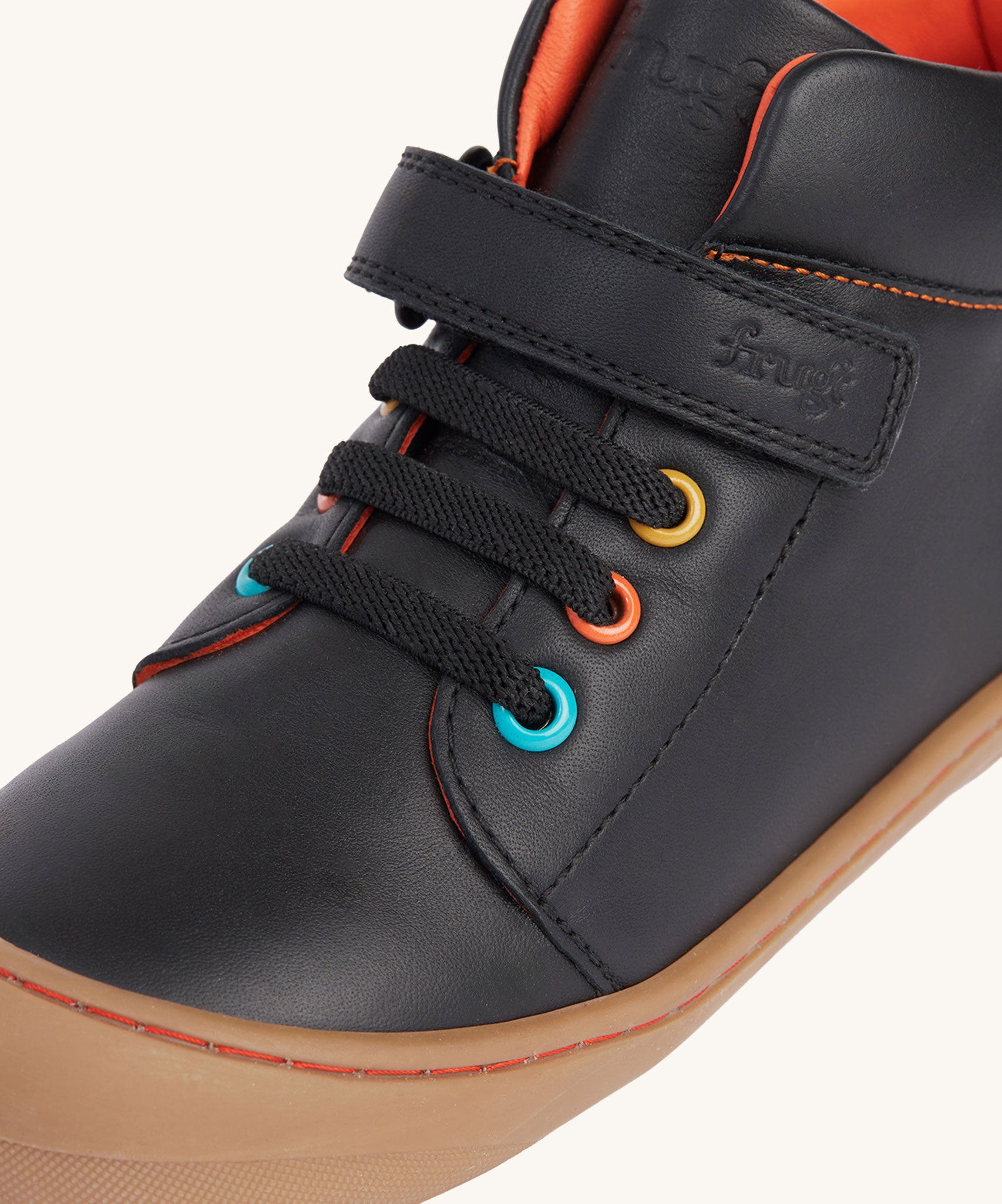 A close up of the coloured eyelets on the Frugi cape stretch children's lace boot in black leather with salamander orange leather lining. 