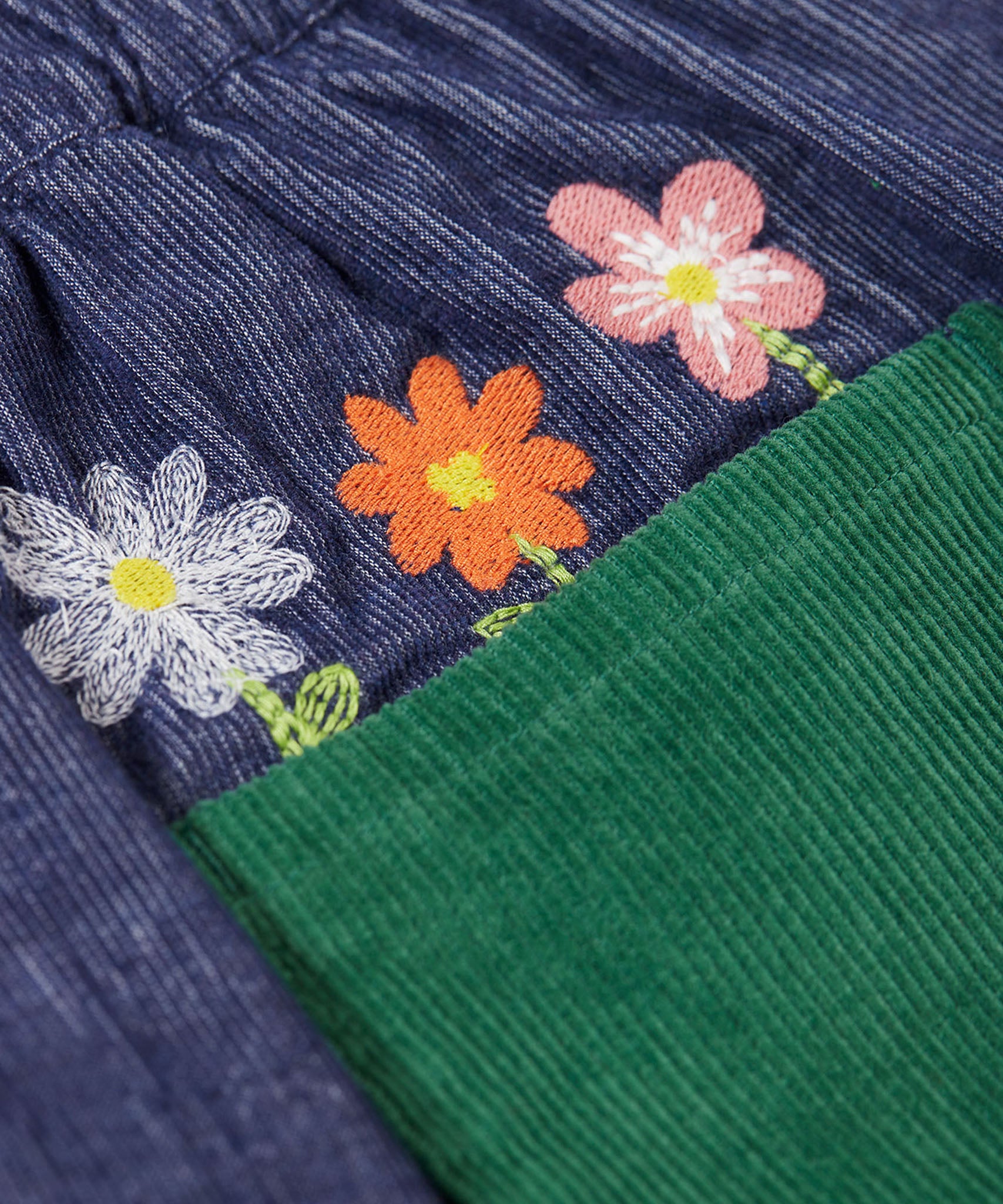 A close up of the embroidered flowers above the back pocket of the Frugi Cara cord children's skirt in ink blue.