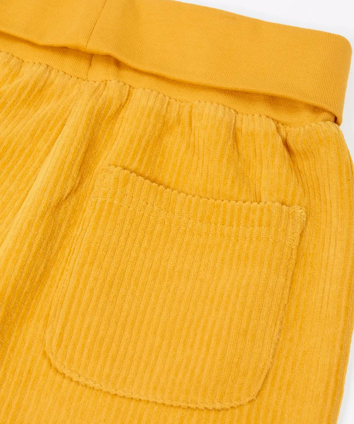 Close up of the back pocket on the Frugi carne organic cotton cord pull up trousers in bumblebee yellow with soft cotton waistband and cuffs that can be folded down for extended wear.