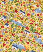 Frugi reversible dungarees showing a close up of the repeating highland cottage print on yellow organic cotton fabric