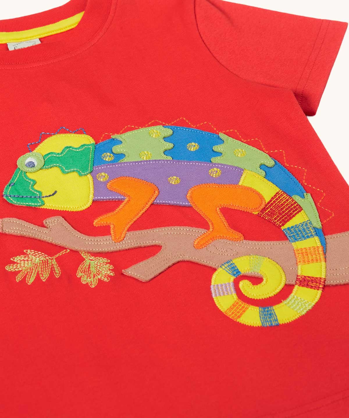 Close up of the multi coloured chamelon on a branch applique on the front of the Frugi red organic cotton short sleeved kids T-Shirt. 