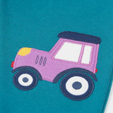 Close up of the purple tractor applique on one side of the Frugi  character joggers in boat blue.