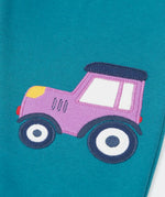Close up of the purple tractor applique on one side of the Frugi  character joggers in boat blue.