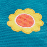 Close up of a yellow flower applique badge on the Frugi cherry boat blue corduroy flared trousers.