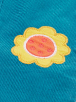 Close up of a yellow flower applique badge on the Frugi cherry boat blue corduroy flared trousers.