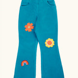Frugi cherry boat blue corduroy flared trousers with two flowers and a rainbow badge stye details. 