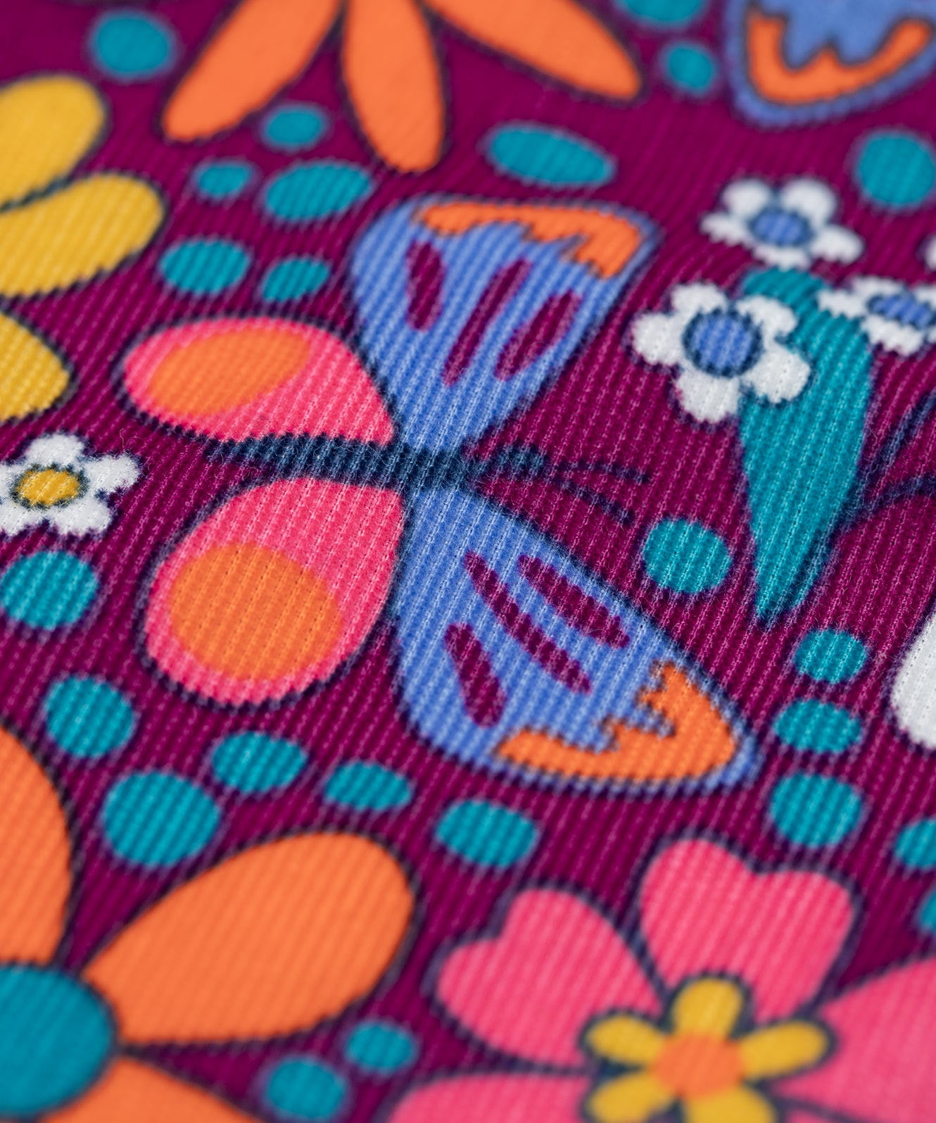 A close up of the detail on the print on the Frugi Organic Cotton Chloe Corduroy Dress for Babies and Toddlers featuring a Retro Floral print design. This dress is a part of a wide range of organic cotton clothing for children available here at Babipur.