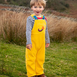 Child wearing the Frugi Gylly cord reversible dungaree in bumblebee yellow with star pocket design.