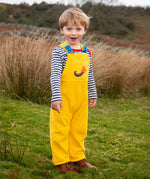 Child wearing the Frugi Gylly cord reversible dungaree in bumblebee yellow with star pocket design.