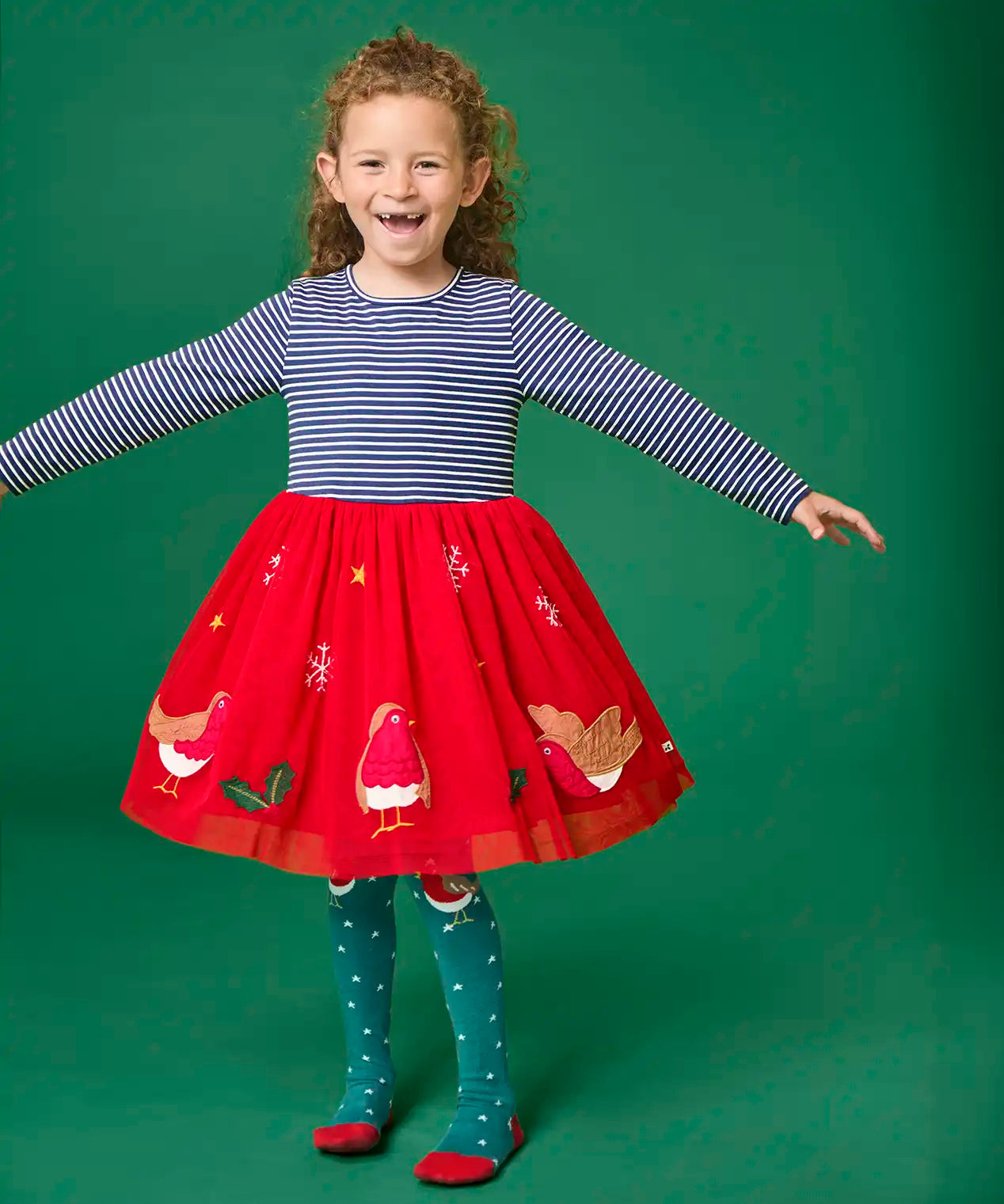 Child wearing the Frugi emmie skater dress with a long sleeved navy stripe top half and red robin applique skirt twirling around.