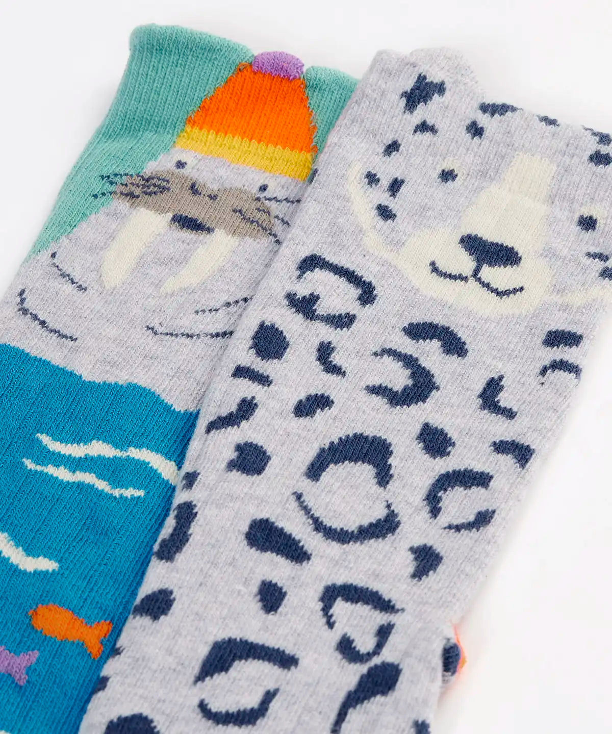 Close up of the Frugi organic cotton character socks 2 pack. One blue pair with a walrus wearing a bobble hat, one pair with a grey leopard.