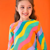 Close up of child wearing the Frugi GOTS organic cotton long sleeved sofia skater dress with a rainbow ric rac pattern.