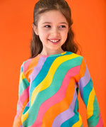 Close up of child wearing the Frugi GOTS organic cotton long sleeved sofia skater dress with a rainbow ric rac pattern.