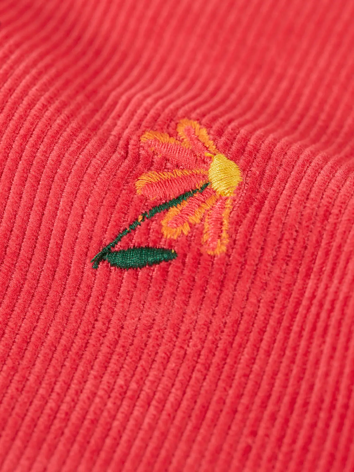 Close up of one of the embroidered flowers on the Frugi children's tabitha rose pink organic cotton corduroy trousers.