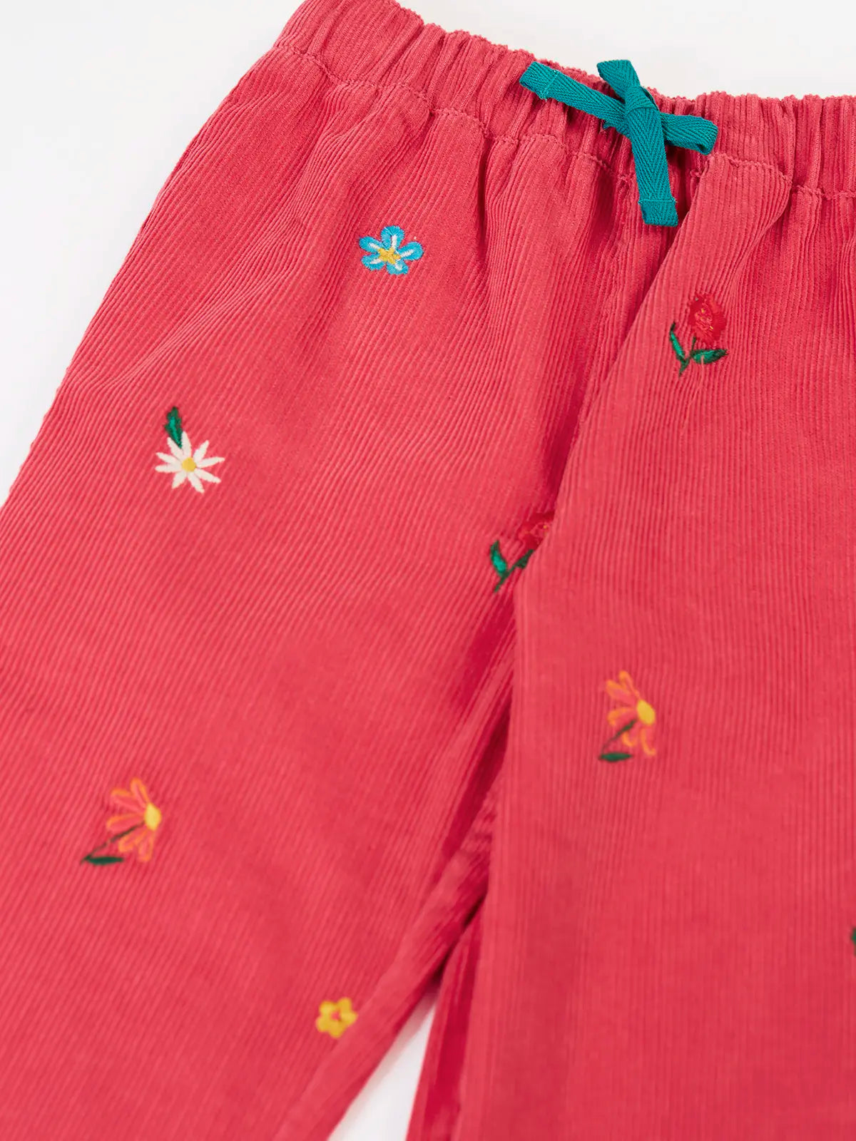 Close up Frugi children's tabitha rose pink organic cotton corduroy trousers with flower embroidery details showing the blue cotton waist tie. 