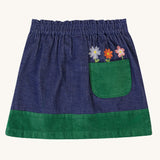 A view of the back of the  Frugi Cara cord children's skirt in ink blue with flower details above a green coloured back pocket. 